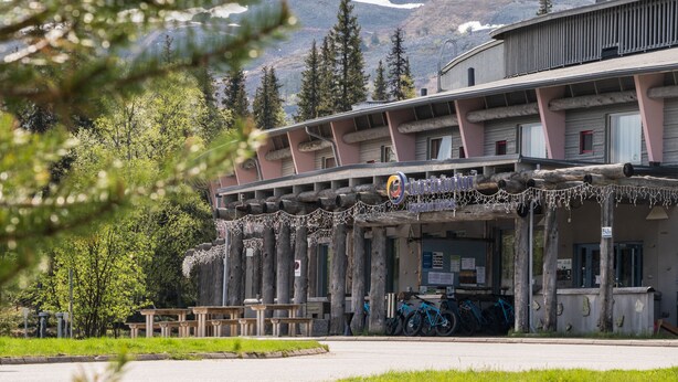 A building with a wooden facade, outdoor seating, and bicycles parked in front. - Lapland Hotels Luostotunturi (Sodankyla)