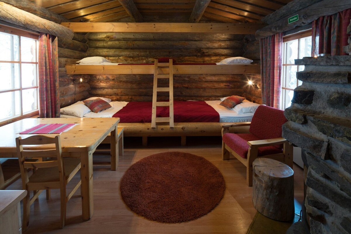 A log cabin room with a bunk bed, a wooden table, chairs, and a rug.