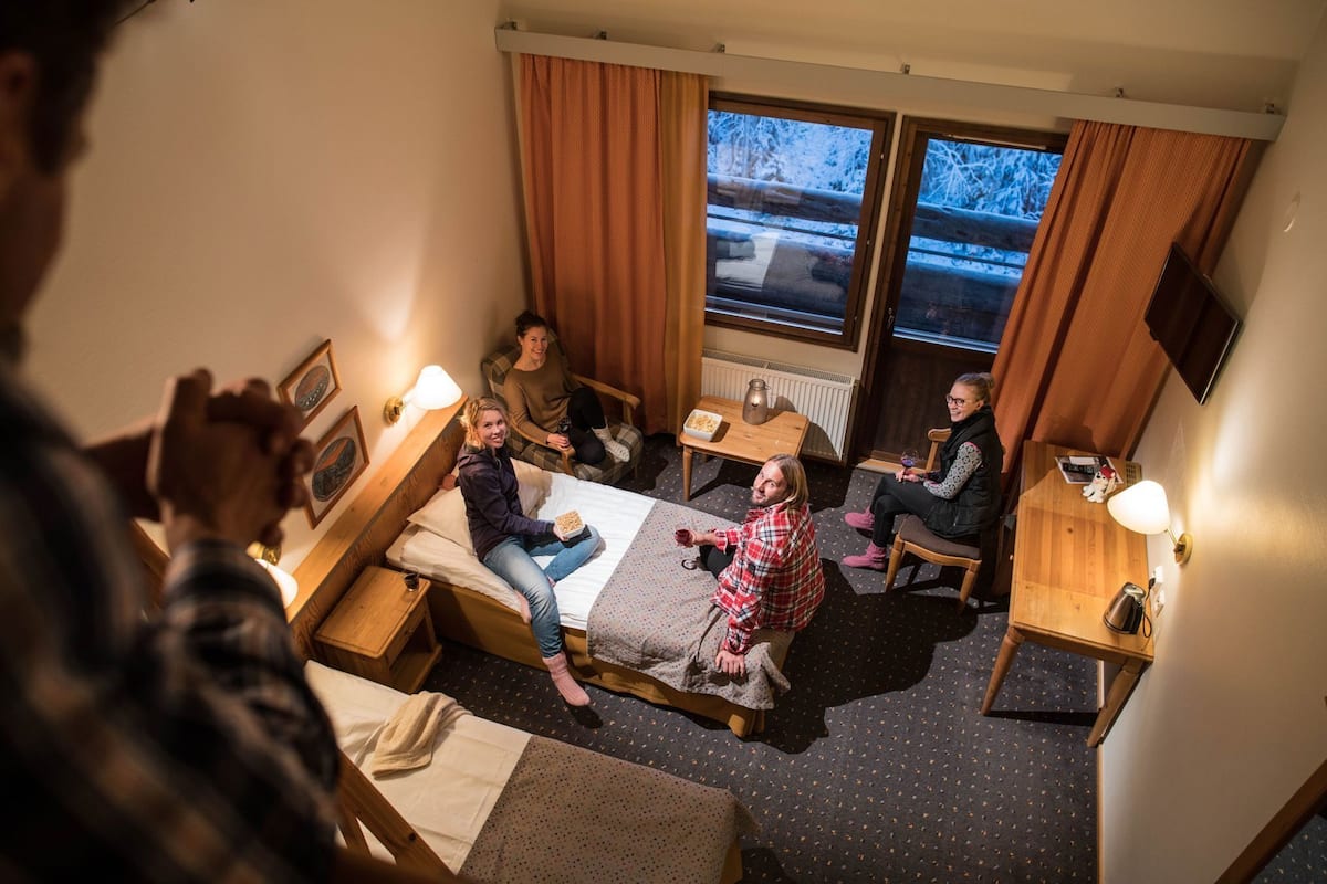 Una habitación de hotel con una cama, dos sillas, una mesita y una ventana con cortinas.