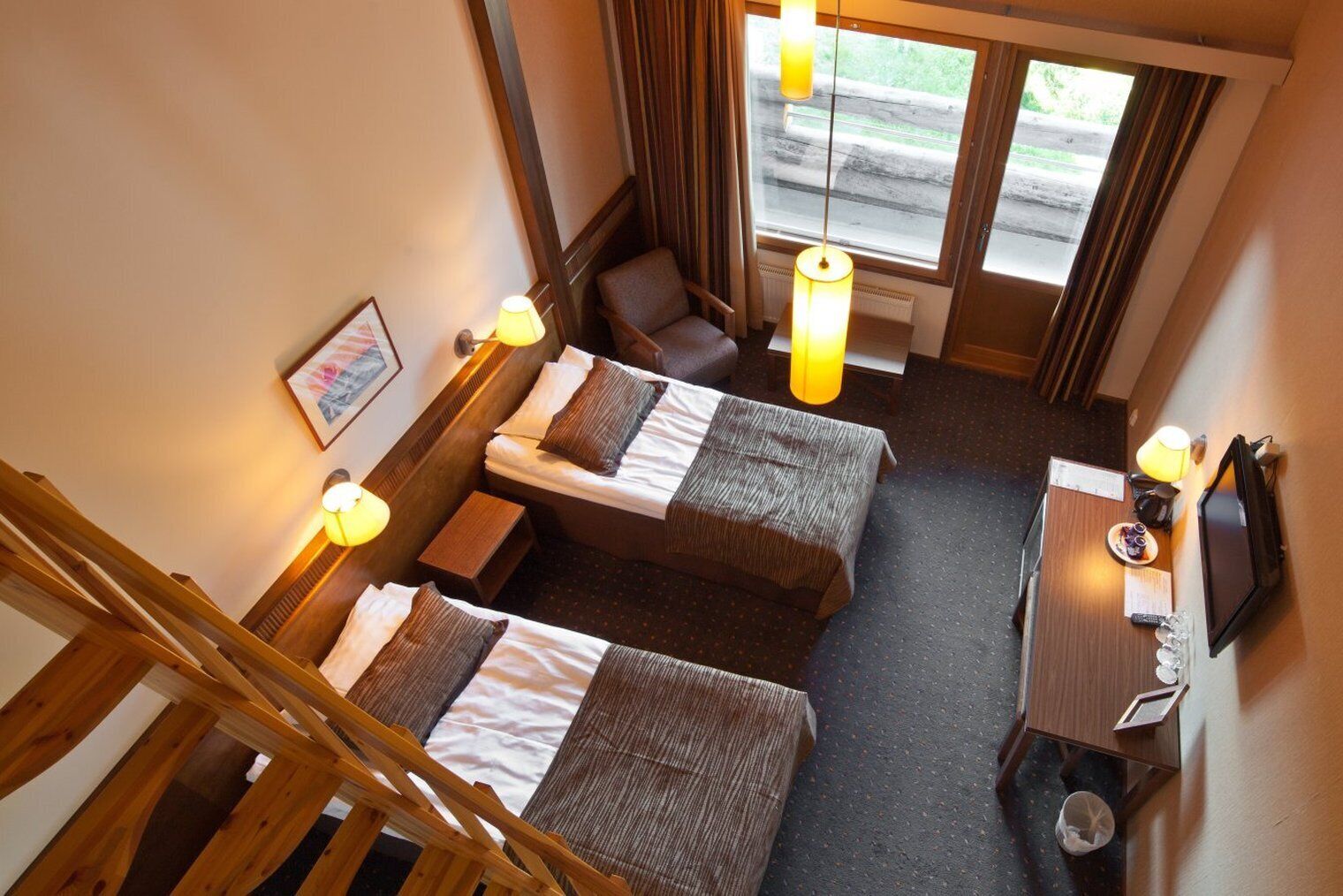 Ein Hotelzimmer mit zwei Betten, einem Schreibtisch, einem Stuhl, einem Fernseher und einem Fenster mit Vorhängen.