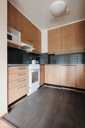A kitchen with wooden cabinets, a white stove, and a black tiled backsplash.