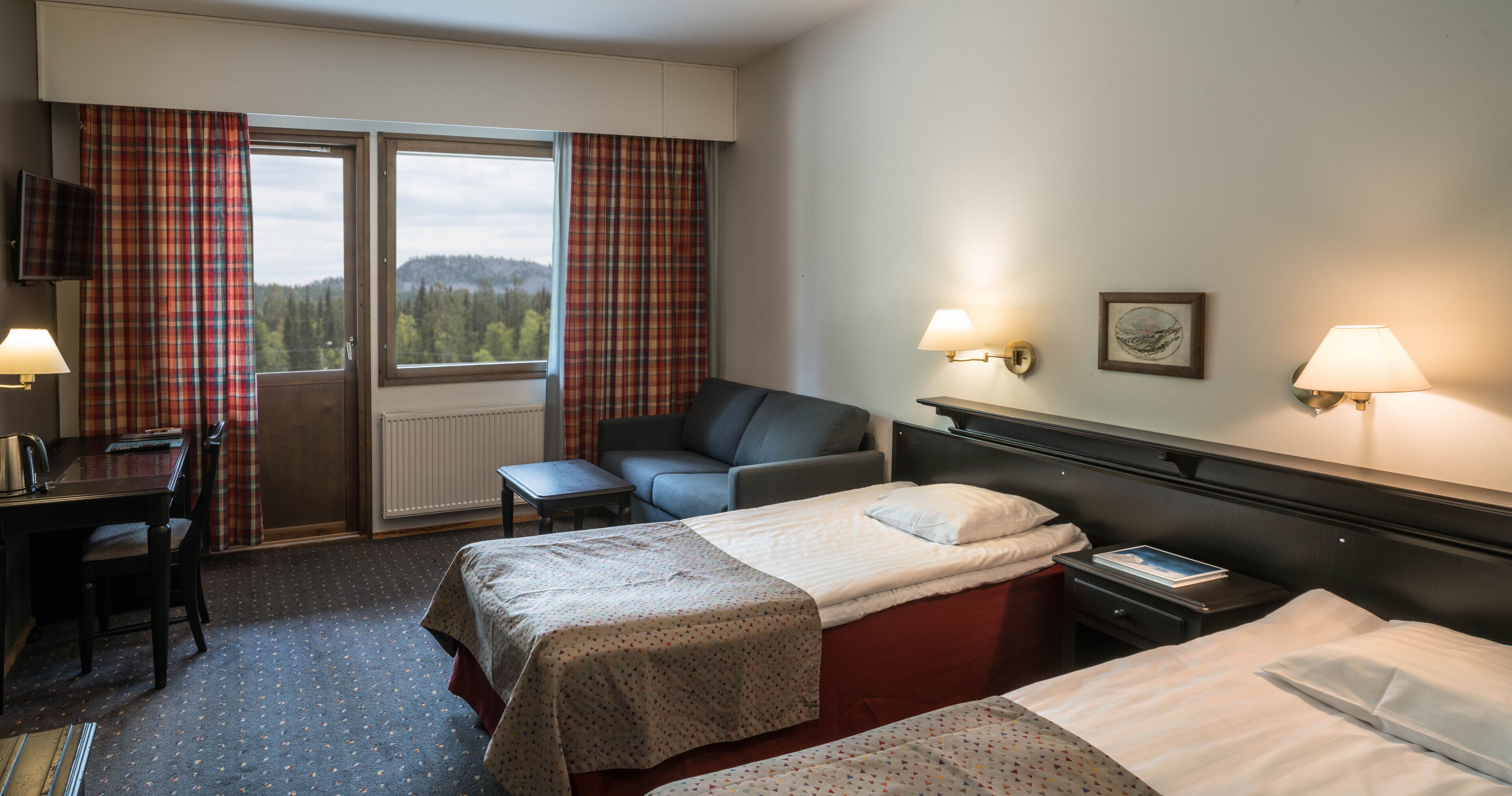 Habitación de hotel con dos camas, un escritorio, una silla y vistas al exterior.