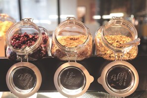 Trois bocaux en verre avec des couvercles en métal, contenant différents aliments, sont disposés sur une surface noire.