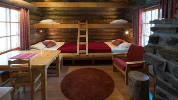 Um quarto de cabana de tronco acolhedor, com beliche, uma mesa de madeira com cadeiras, tapete vermelho e parede de pedra.