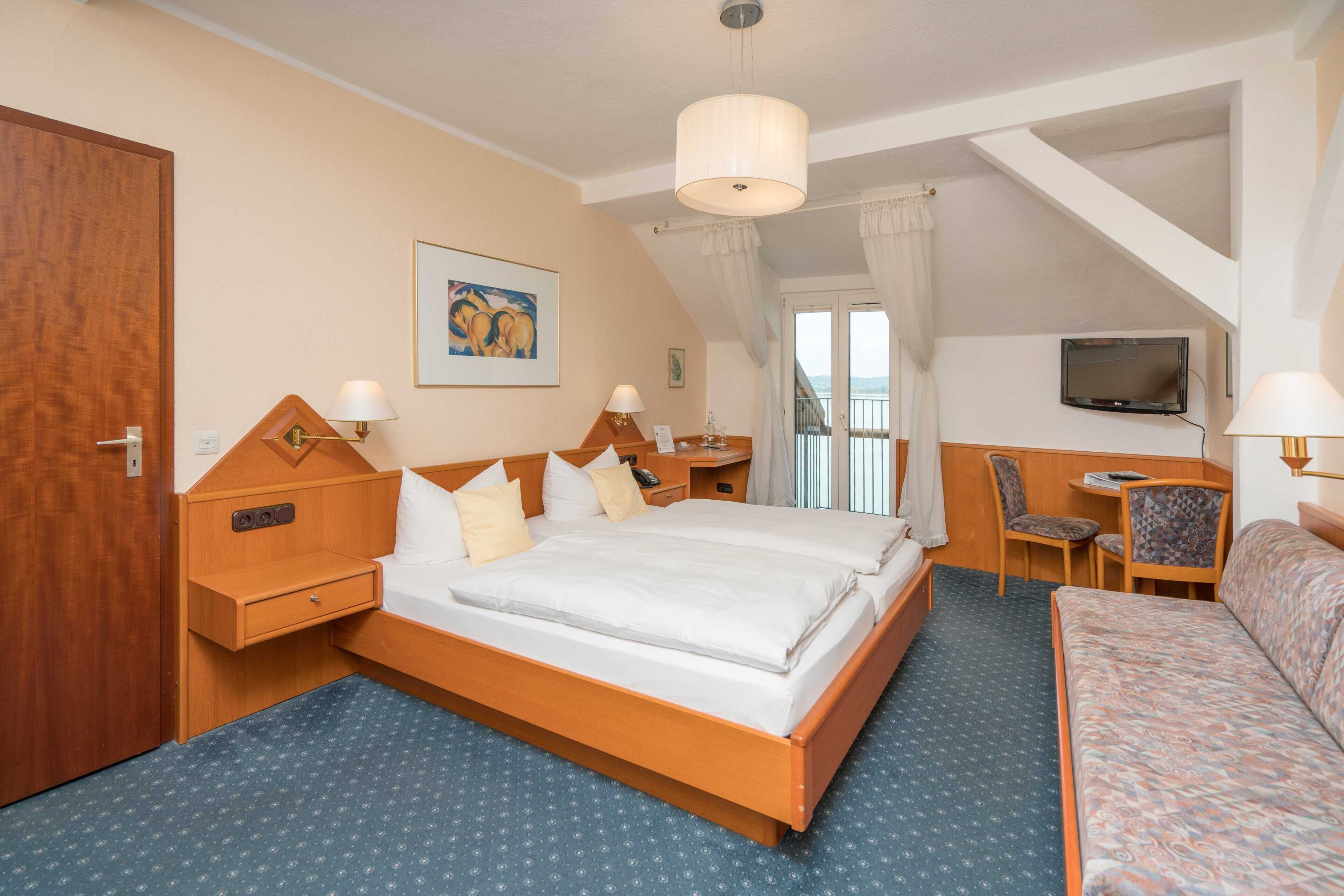Une chambre d’hôtel avec un grand lit, un bureau, une chaise, une télévision et un balcon avec vue.