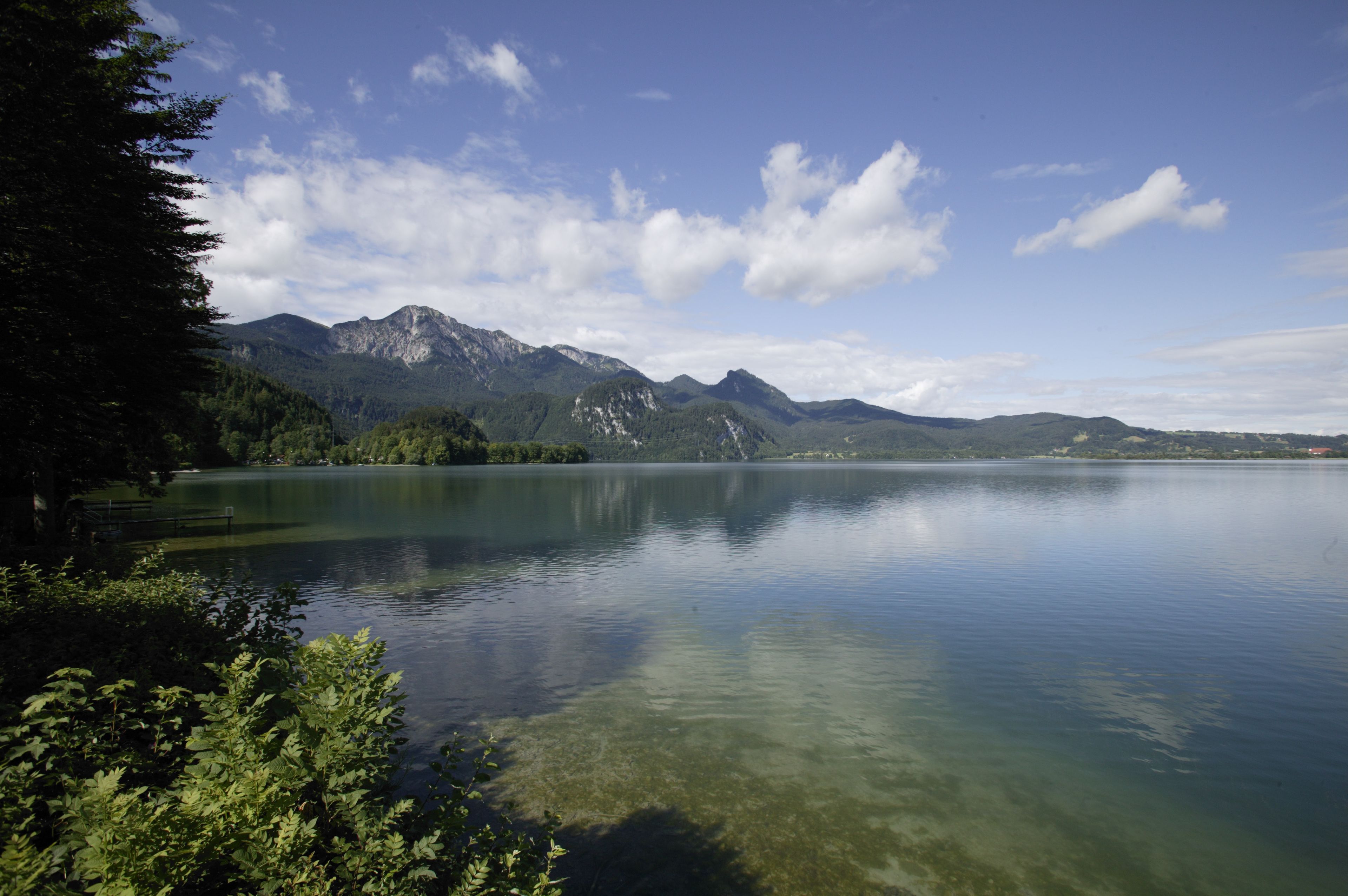 A serene lake with mountains in the background and clear water reflecting the sky.