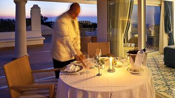 Une table dressée pour un dîner à deux, avec une bougie, une carafe et un verre d’eau.