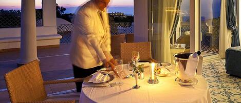 A dining table set for two with a candle, a pitcher, and a glass of water.