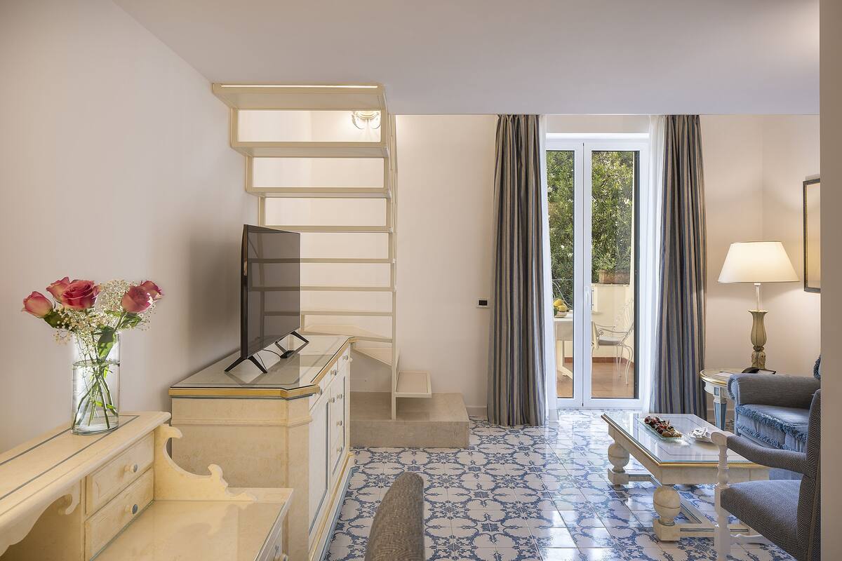 Ein Hotelzimmer mit Treppe, Essbereich und Blick durch die Glastüren.