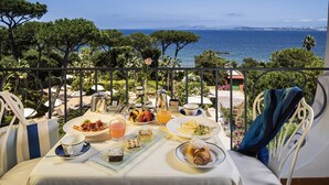 A table set for breakfast with a view of the sea, outdoor seating, and a balcony railing. - Excelsior Belvedere Hotel & Spa (Ischia)