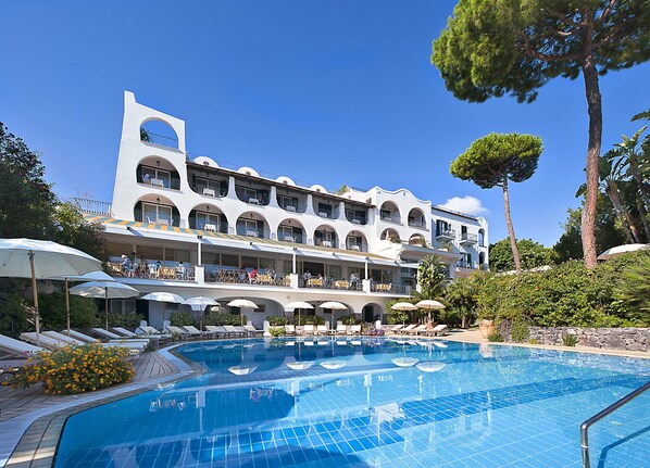 A hotel with a swimming pool, multiple balconies, and outdoor seating areas.