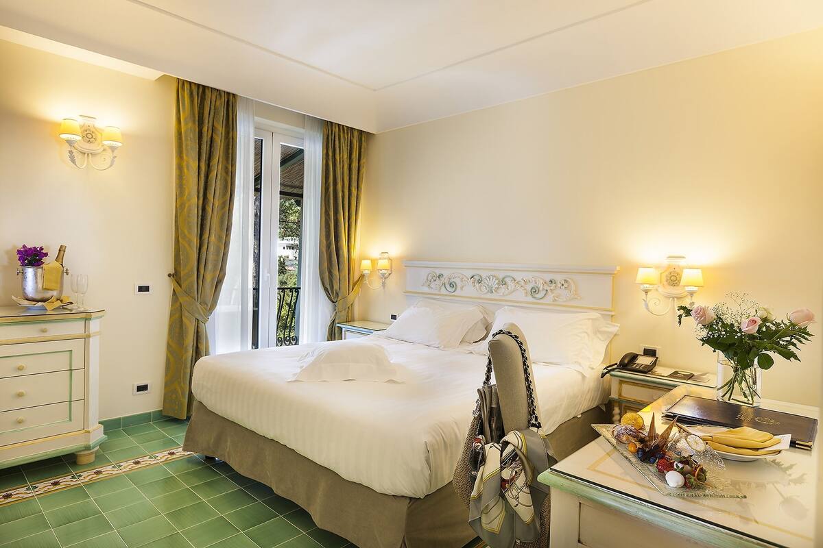 Ein Hotelzimmer mit Bett, Nachttisch mit Telefon, Kommode und Tablett mit Früchten und Gebäck.