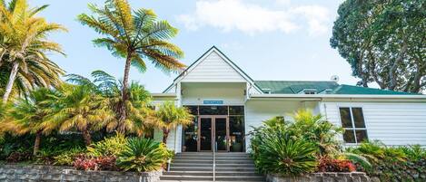 A reception area with a sign, steps leading up to the entrance, and tropical plants around the building.