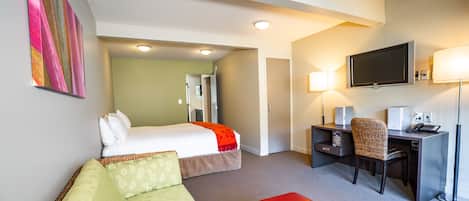 Habitación de hotel con cama, escritorio, silla, televisor y sofá.