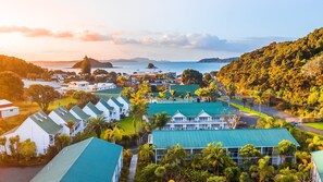 A coastal resort with multiple buildings, including a prominent hotel with a green roof, surrounded by lush greenery and a view of the sea. - Scenic Hotel Bay of Islands (Paihia)