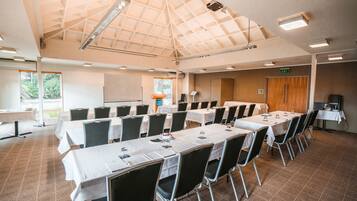 A conference room with multiple tables and chairs, a whiteboard, and a podium.