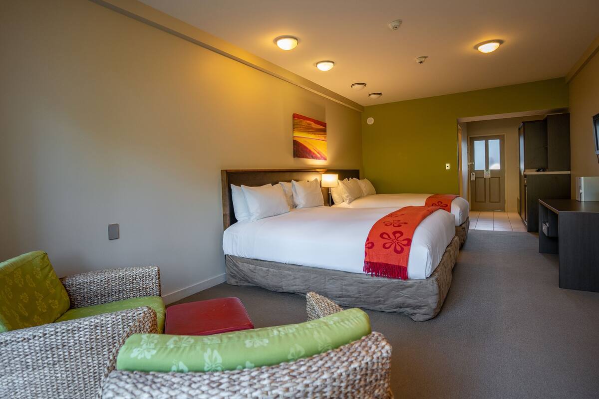 A hotel room with a large bed, a desk, and a seating area with cushions.
