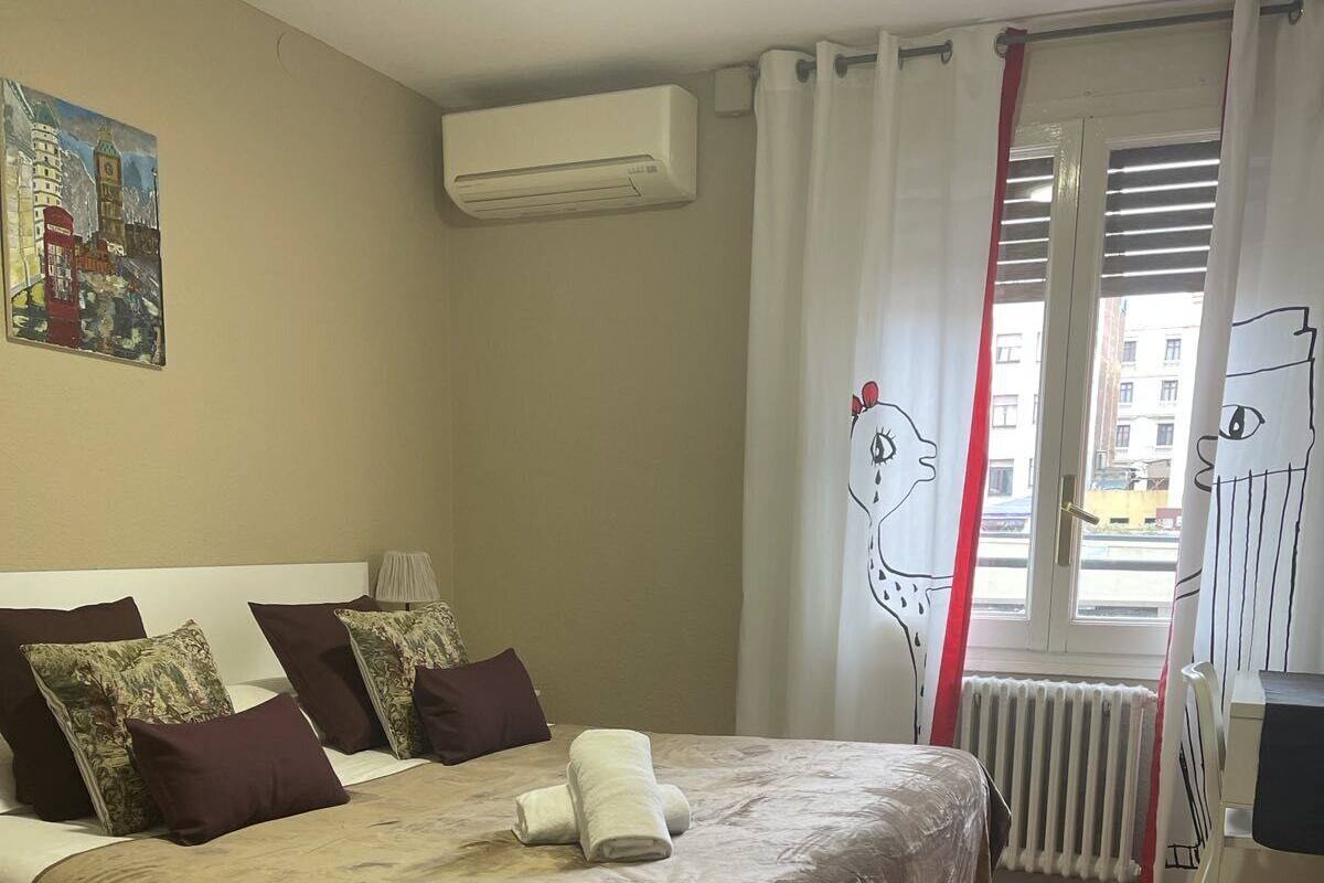 A bedroom with a bed, a radiator, and a window with curtains.