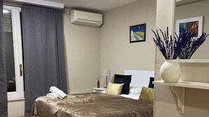 A bedroom with a bed, a nightstand, a lamp, an air conditioning unit, and a window with curtains. - Somnio Hostels (Barcelona)