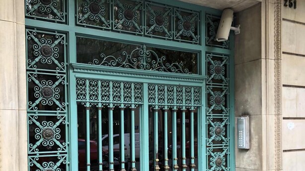 A large, ornate metal gate with intricate designs and a keyhole, set in a stone building. - Somnio Hostels (Barcelona)