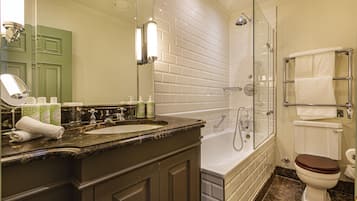 A bathroom with a marble sink, a glass-enclosed shower, a white toilet, and a towel rack.