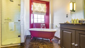 A bathroom with a clawfoot bathtub, a glass shower enclosure, and a vanity with toiletries.