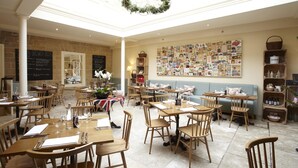 Un restaurant avec des tables et des chaises en bois, un mur recouvert de photos et un lustre.