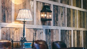 Un intérieur rustique avec un mur en bois, une table avec une lampe et des fauteuils en cuir.