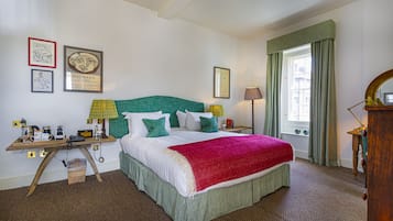 A neatly arranged bedroom with a bed, bedside tables, lamps, and framed artwork on the walls.