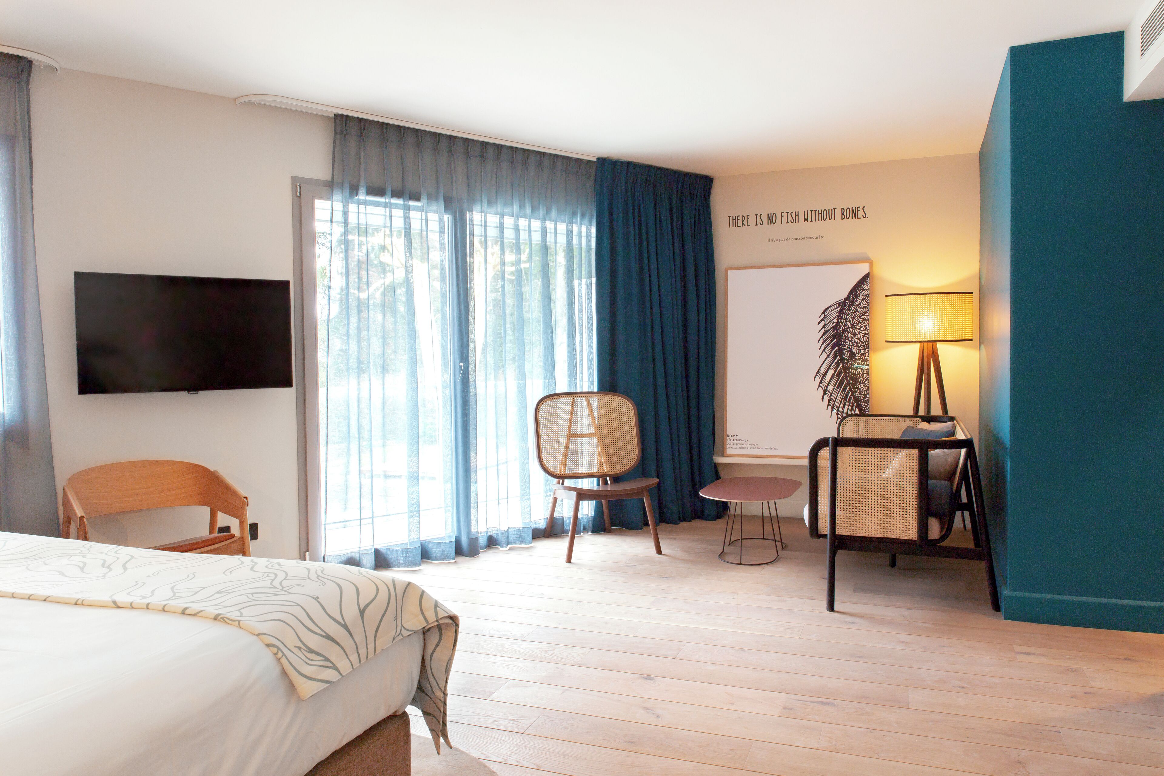 A hotel room with a bed, a TV, a desk with a chair, and a window with curtains.