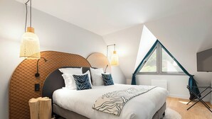 Un dormitorio moderno con cabecera curva, una cama grande con almohadas estampadas y un tragaluz.