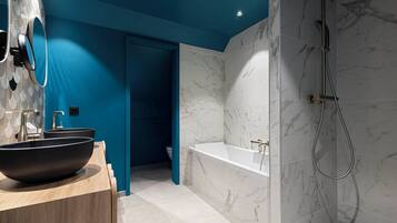 Une salle de bain moderne avec un grand lavabo noir sur pied, une baignoire blanche et une douche équipée d’un flexible.