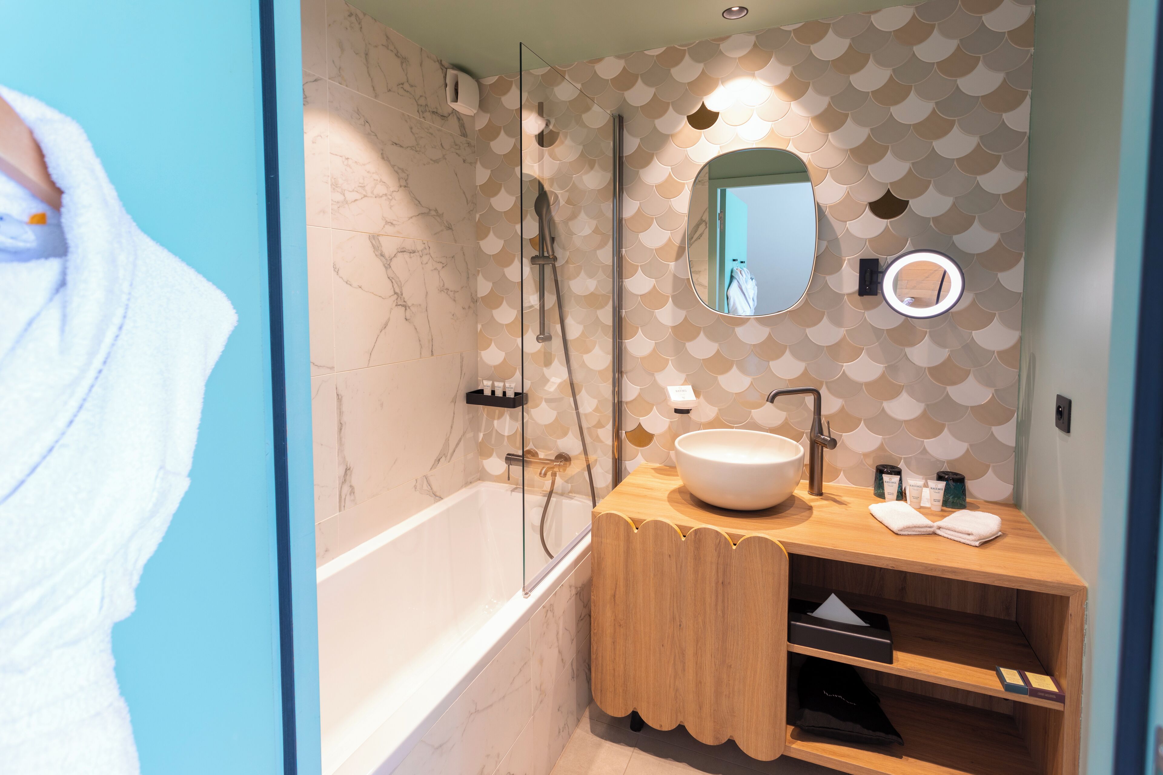 A modern bathroom with a bathtub, a wooden vanity with a sink, and a mirror.