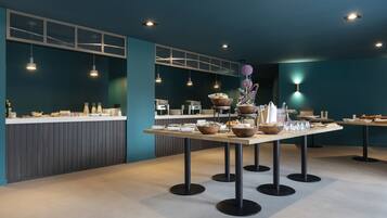 A modern dining area with tables set for a meal, featuring a teal color scheme and contemporary lighting.