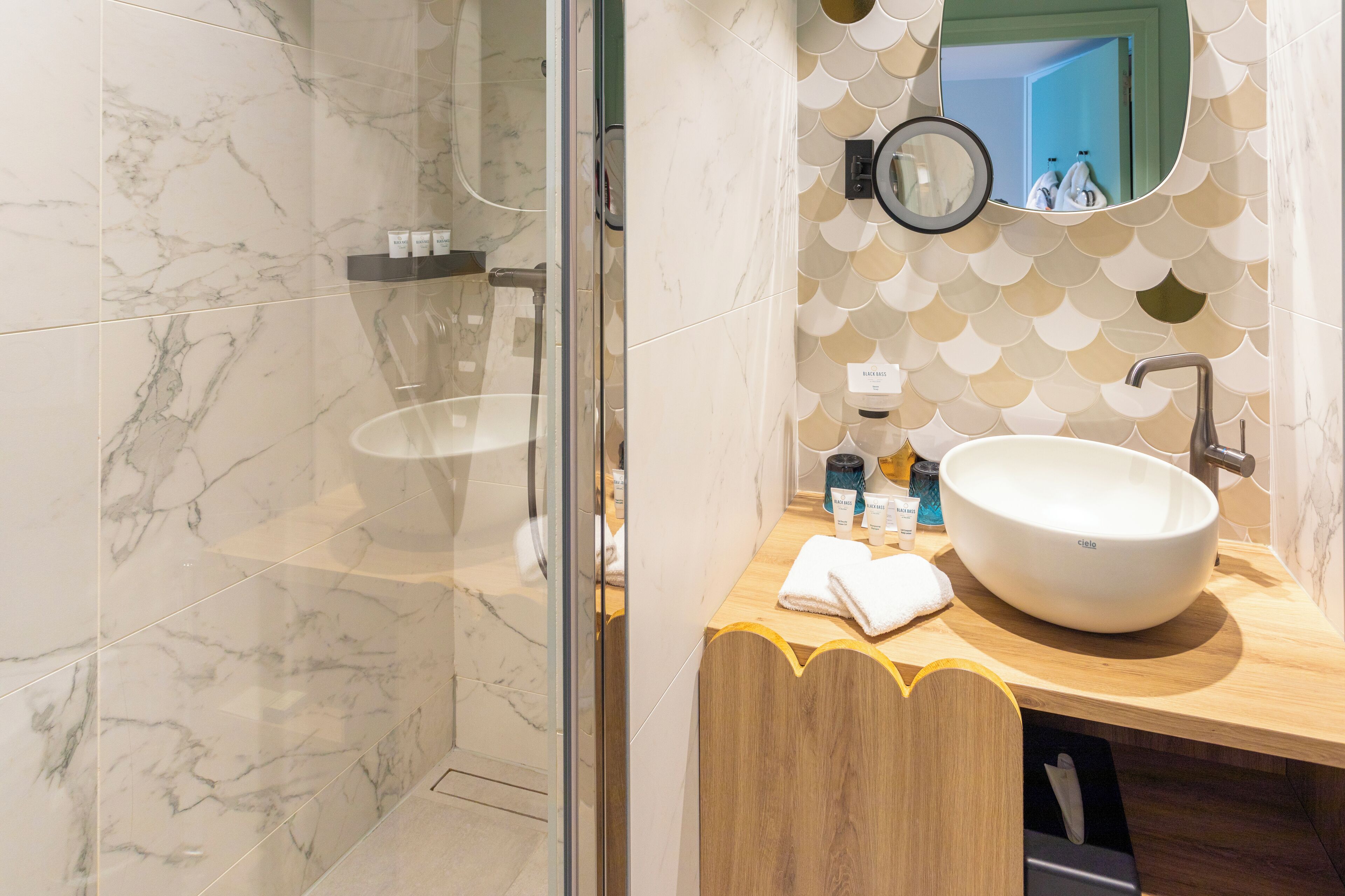 Une salle de bain moderne avec un grand lavabo blanc, un miroir et un espace douche.