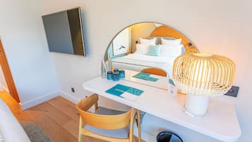 Ein Hotelzimmer mit einem Bett, einem Schreibtisch mit Stuhl, einem an der Wand befestigten Fernseher und einer Lampe.