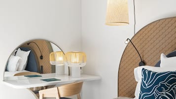 Una habitación de hotel moderna con una cama redonda, un escritorio con dos lámparas, una silla y un espejo grande.