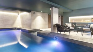 Un área de piscina interior moderna con asientos y un bar.