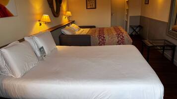 Quarto de hotel com uma cama grande, duas mesas de cabeceira com abajures, uma pequena escrivaninha e uma cadeira.
