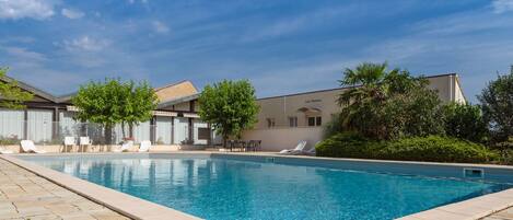 A swimming pool with lounge chairs and a building in the background.