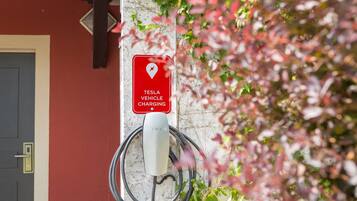 A Tesla vehicle charging station mounted on a wall with a red sign indicating charging availability.