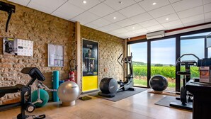 A gym with exercise equipment, a wall clock, and a bulletin board. - KYRIAD PRESTIGE BEAUNE - Le Panorama (Beaune)