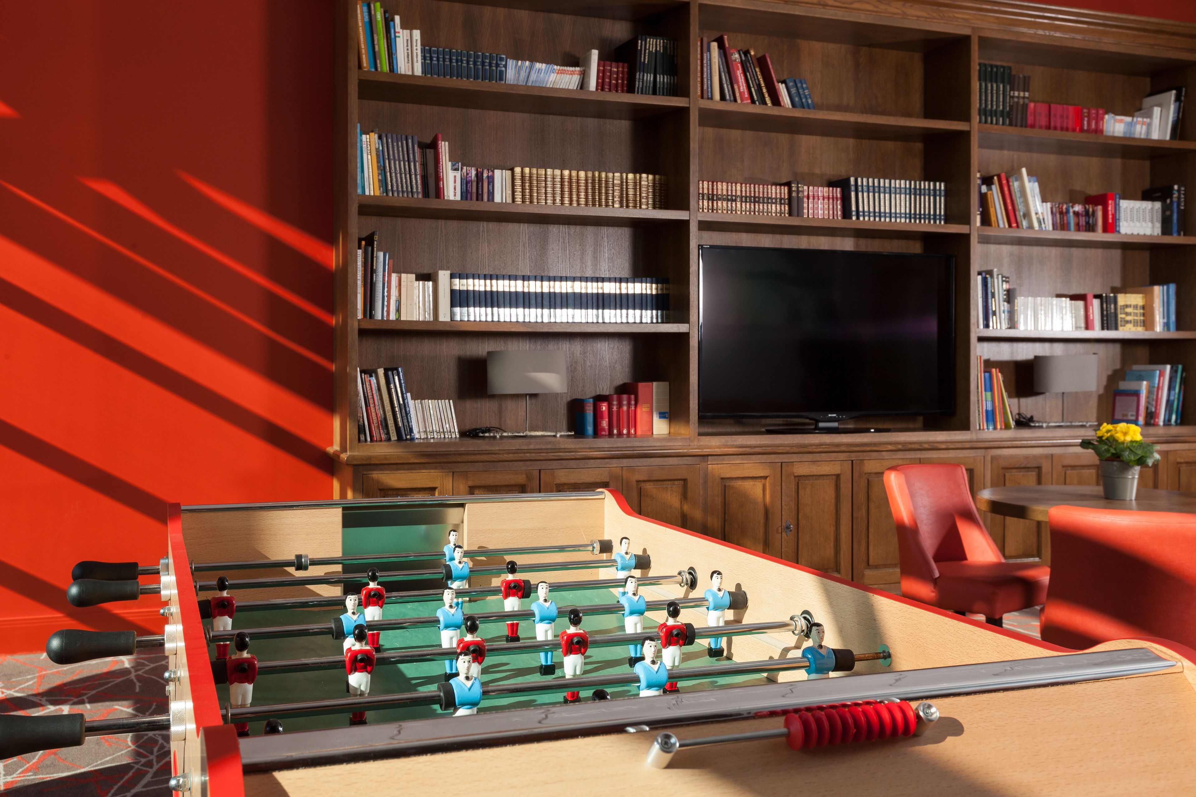 Una mesa de fútbol de mesa en una habitación con una estantería y un televisor.