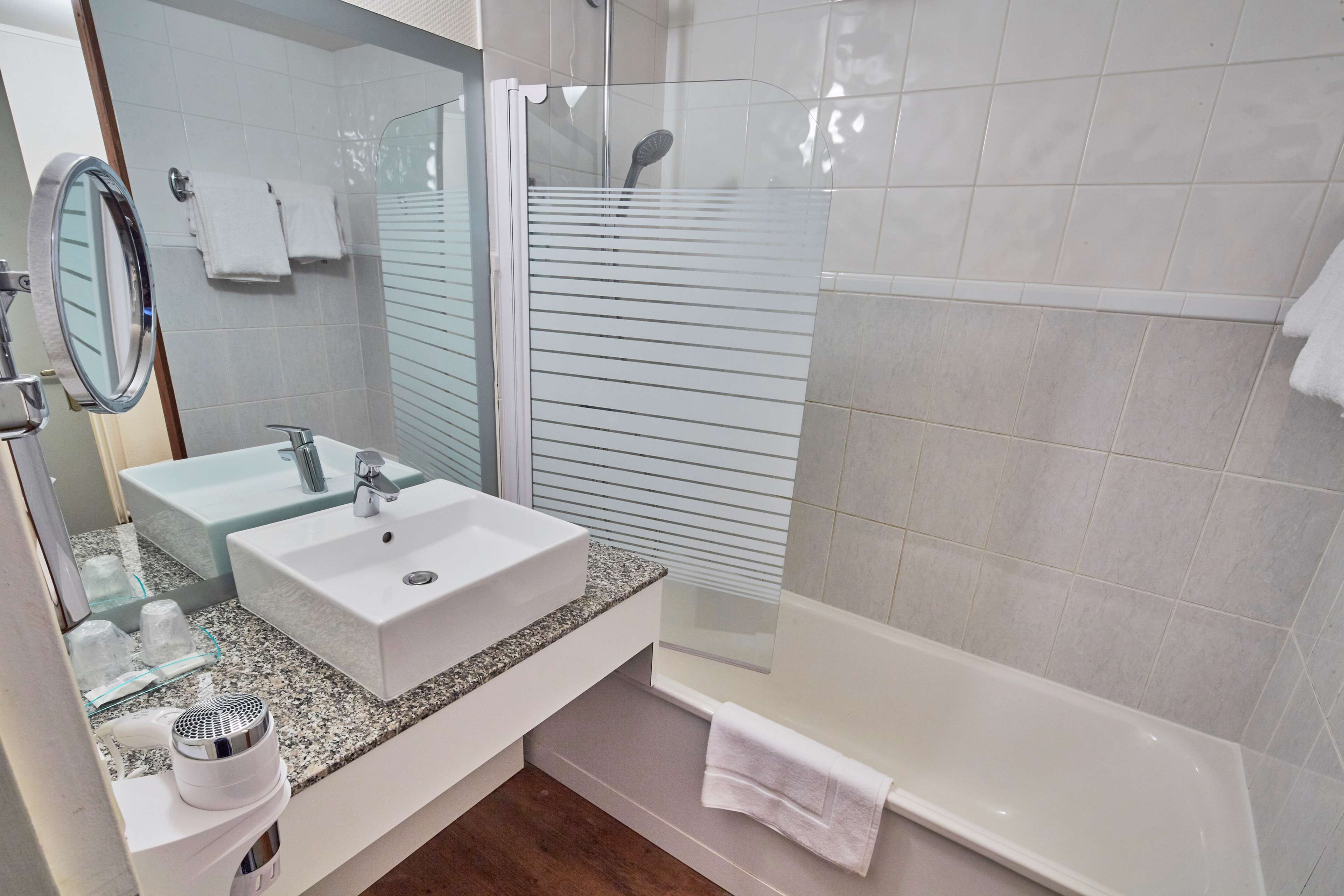 A modern bathroom with two sinks, a large mirror, a shower enclosure, and a bathtub.