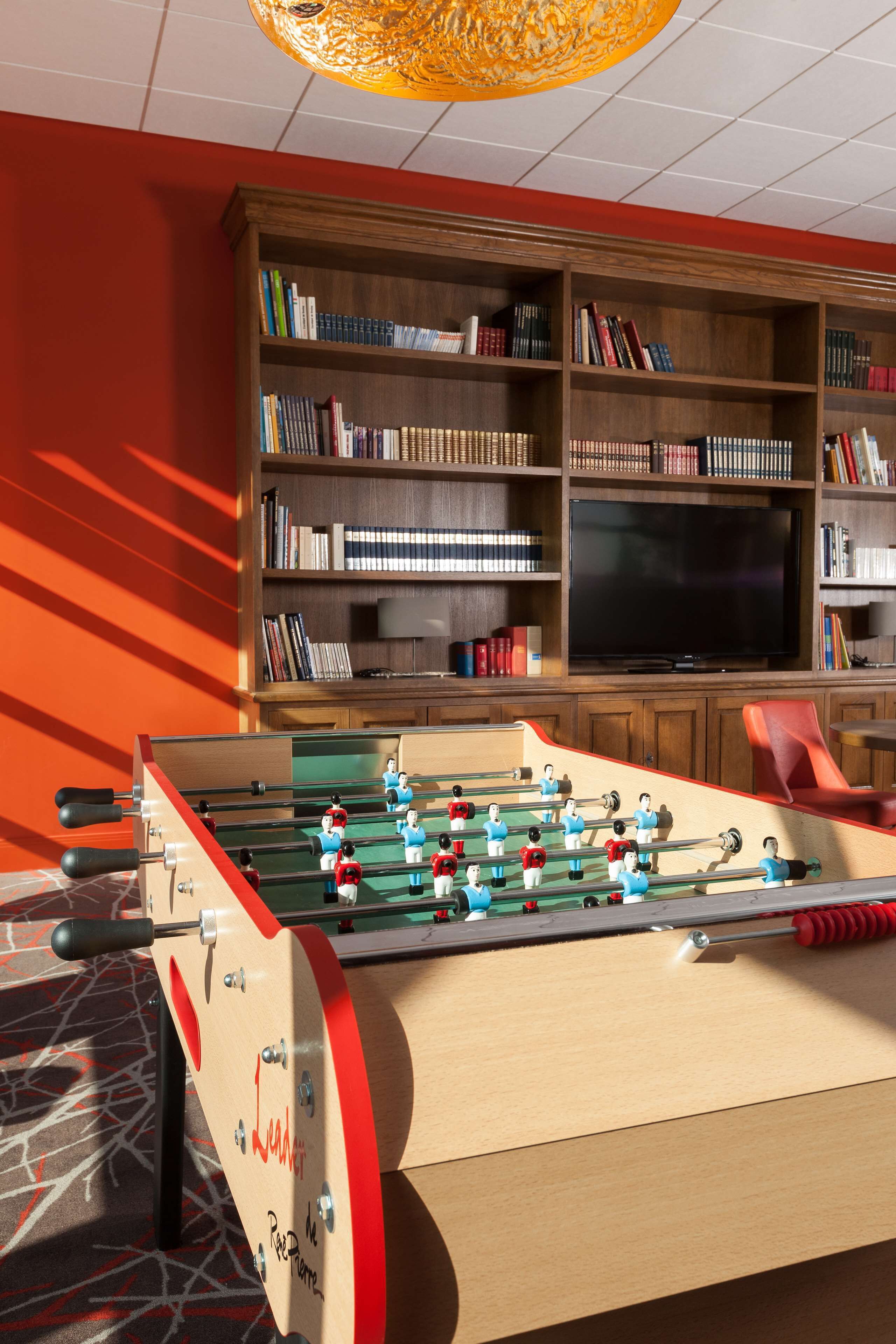 Una mesa de fútbol de mesa en una habitación con una estantería y un televisor.