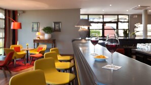 A bar area with yellow chairs, a table with a wine glass, and a lamp. - KYRIAD PRESTIGE BEAUNE - Le Panorama (Beaune)