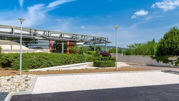 Un edificio moderno con pasarela cubierta, jardín ajardinado y zona de estacionamiento.