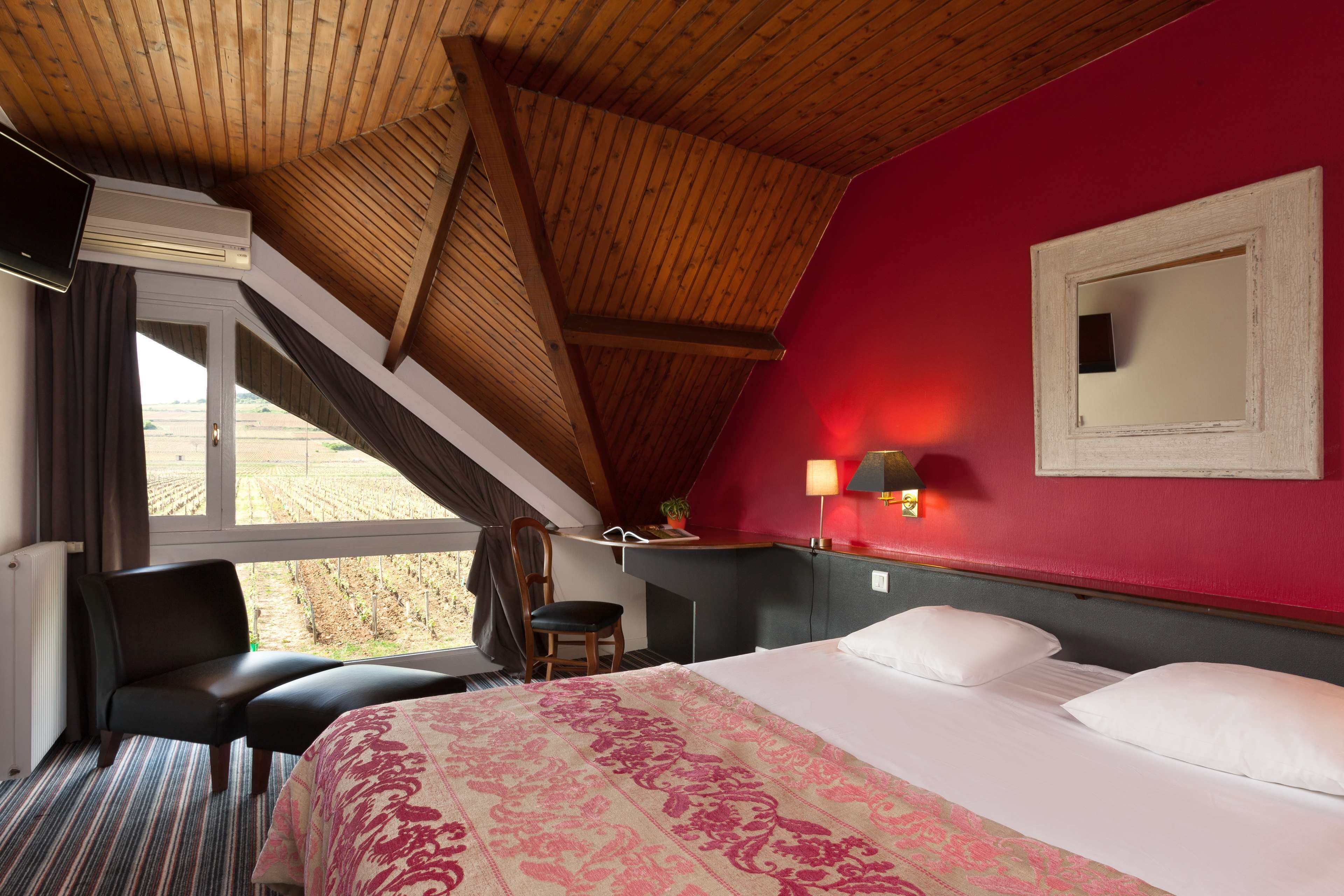 Une chambre d’hôtel avec un grand lit, un bureau, une chaise et une fenêtre donnant sur la campagne.