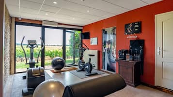 Un gimnasio con equipo de ejercicio, una pelota de ejercicio grande y vistas al exterior.