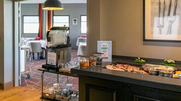 Uma área de buffet com uma máquina de café, diversos recipientes de comida e uma placa indicando produtos congelados.